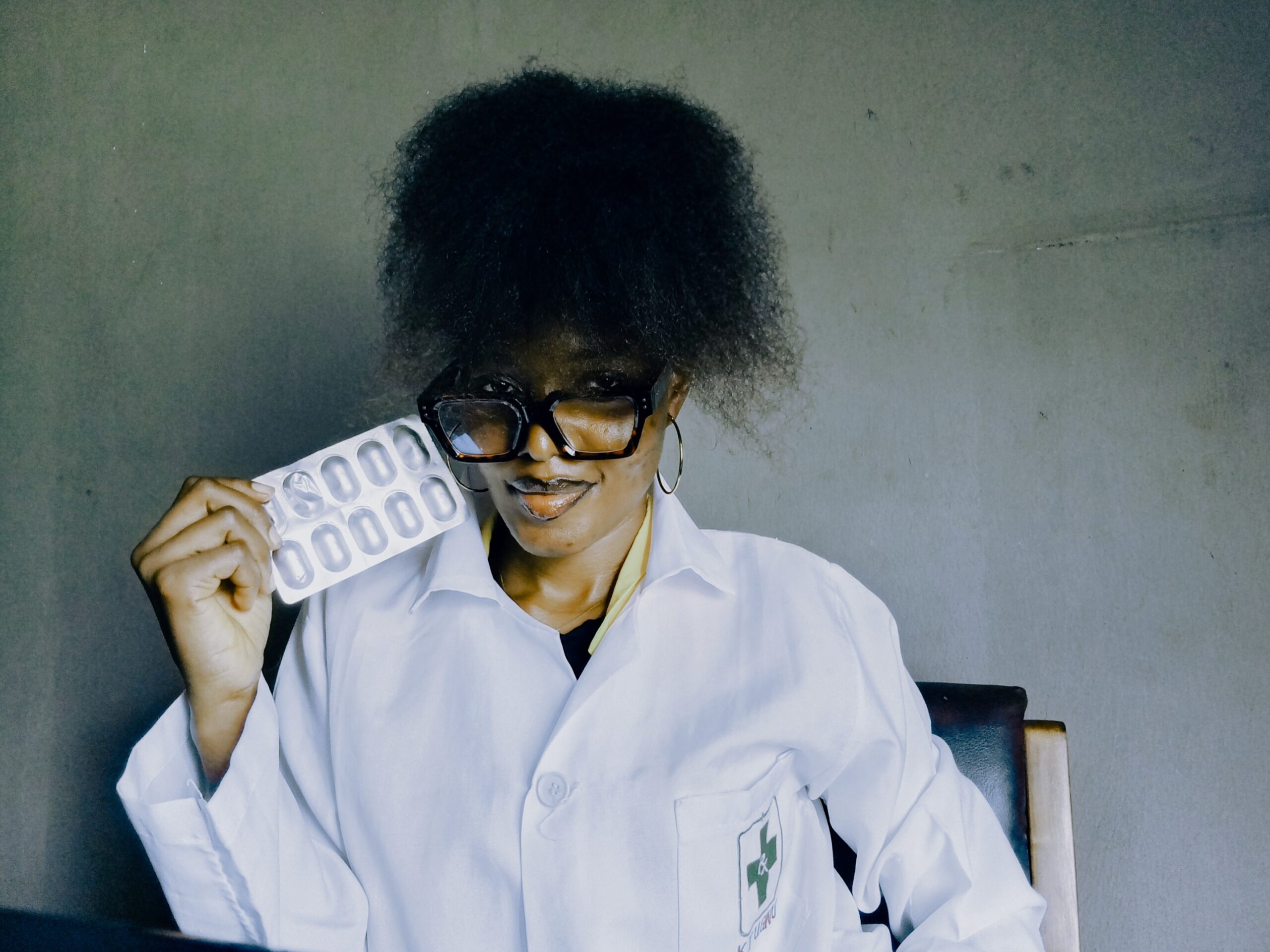 Pharmacist in Enugu community pharmacy holding drug blister pack during locum job after UNN graduation